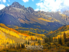 Mt Sneffels in autumn with aspen trees displaying vibrant yellow and orange fall foliage. The snow-capped peaks of the San Juan Mountains contrast with the colorful valley below, which is highlighted by rays of sun highlighting the fall colors near Ridgway.  Colorado Fine Art Landscape Photography Print for Sale.
