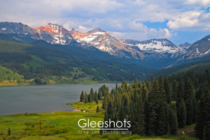 Trout Lake is featured in this stunning mountain landscape near Telluride Colorado.  The sunlit peaks of the copper-colored San Juan Mountains, partially covered in snow, loom above the lake.  Sunlight shining through the clouds creates interesting shadows on the landscape below.  Colorado Fine Art Landscape Photography Print for Sale.
