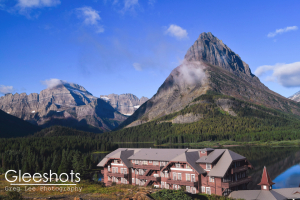 The historic Many Glacier Hotel and Swiftcurrent Lake in Glacier National Park, with light wispy clouds among a clear blue sky.   Montana Fine Art Landscape Photography Print for Sale.