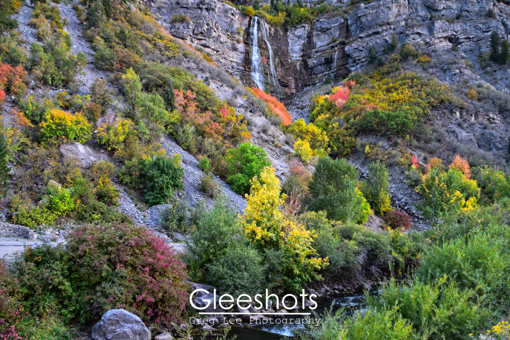 Bridal Veil Falls cascades down the side of the mountain in the background, with the Provo River and vibrant green, yellow, and red foliage in the foreground of this autumn scene.   Utah Landscape Photography Print for Sale.