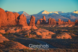 The red rock formations of the Garden of Eden in Arches National Park glow in the warm light of sunset.  The snow-capped La Sal mountains are highlighted in the background.  Utah Fine Art Landscape Photography Print for Sale.