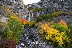 Bridal Veil Falls cascades down the mountain in Provo Canyon, surrounded by trees with vibrant autumn foliage in hues of yellow, orange, red, and green. Utah Landscape Photography Print for Sale.