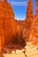 Hikers walk along the Navajo Loop Trail in Bryce Canyon, a winding trail between towering orange rock formations.  Utah Fine Art Landscape Photography for Sale.