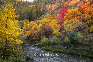 Fifth Water Hot Springs Creek flows through a forest with vibrant fall foliage in shades of yellow, red, and orange, set against rocky cliffs.  Utah Fine Art Landscape Photography for Sale.