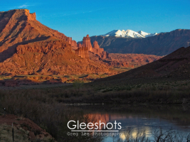 The red rock Fisher Towers are the centerpiece of this photo along the Colorado River outside of Moab.  Snow-covered mountains can be seen in the distance.   Utah Fine Art Landscape Photography for Sale.