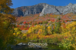 Colorful autumn foliage in red, orange, purple, and yellow covers a hillside in Provo Canyon, with the Provo River in the foreground.   Utah Fine Art Landscape Photography for Sale.