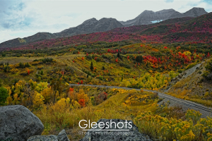 The foothills of Mt Timpanogos in autumn, with foliage displaying shades of red, yellow, and green.   Large boulders dot the foreground.  Utah Landscape Photography for Sale.